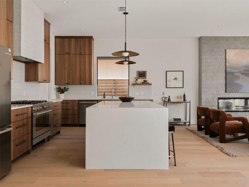 Kitchen featuring light stone counters, a kitchen island, pendant lighting, modern cabinets, and recessed lighting