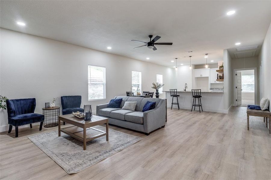 Living room featuring sink, light wood-type flooring, and ceiling fan