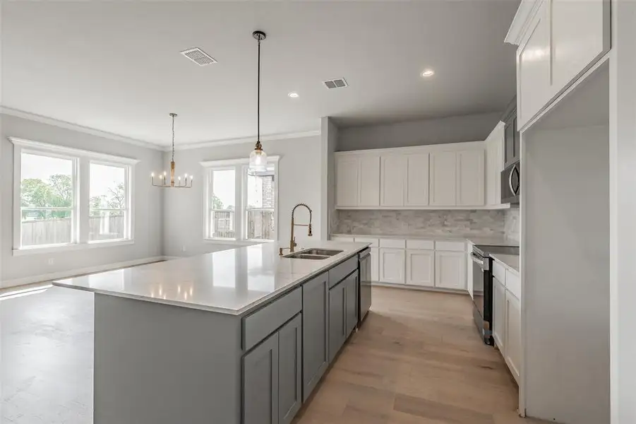 Kitchen is a chef's dream equipped with quartz countertops, an island, SS appliances, tons of cabinet space & counterspace & a walk in pantry