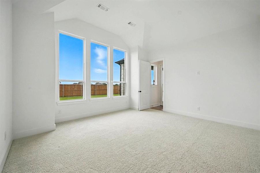 Unfurnished room featuring light colored carpet and lofted ceiling