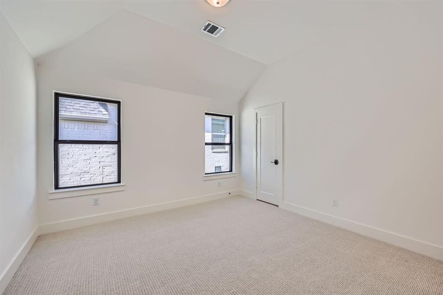 Carpeted empty room featuring vaulted ceiling