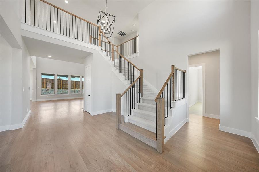 Staircase with wood finished floors, a high ceiling, a chandelier, and recessed lighting Staircase with wood finished floors, a high ceiling, a chandelier, and recessed lighting