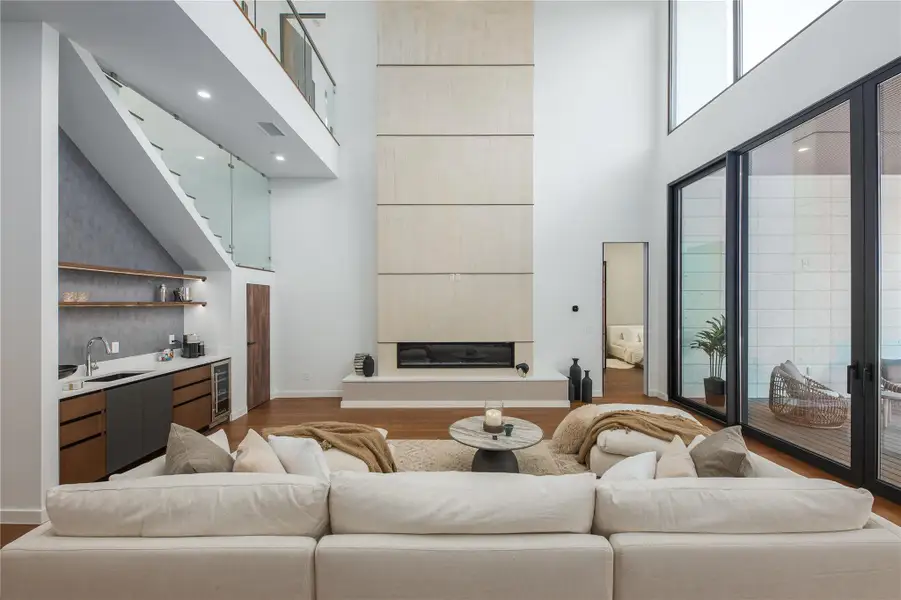 An impressive fireplace commands this spacious living area, complemented by soaring ceilings and hardwood floors.