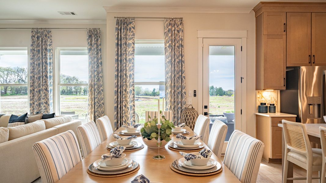Dining area looking out the back of the home, with set table near windows and kitchen