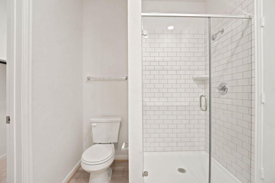 Crisp subway tile lines the glass-enclosed walk-in shower adjacent to the main toilet area.