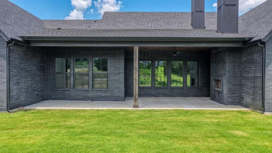 Expansive covered patio featuring a concrete surface, a built-in outdoor fireplace, and a ceiling fan
