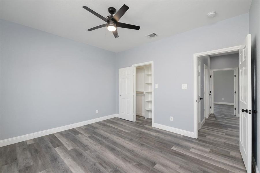 Unfurnished bedroom featuring a spacious closet, wood finished floors, and ceiling fan Unfurnished bedroom featuring a spacious closet, wood finished floors, and ceiling fan
