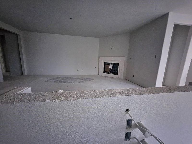Unfinished interior space featuring a built-in fireplace surround, recessed wall for entertainment components, and a partial wall element Unfinished interior space featuring a built-in fireplace surround, recessed wall for entertainment components, and a partial wall element