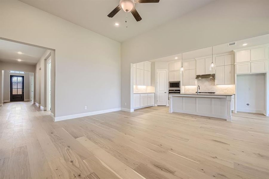 Unfurnished living room featuring light hardwood / wood-style floors, ceiling fan, and sink