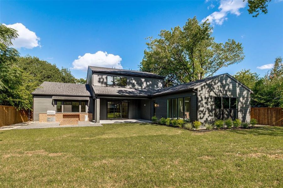 Expansive backyard featuring a manicured lawn, a large patio space, and a built-in outdoor kitchen with brick-finish accents Expansive backyard featuring a manicured lawn, a large patio space, and a built-in outdoor kitchen with brick-finish accents