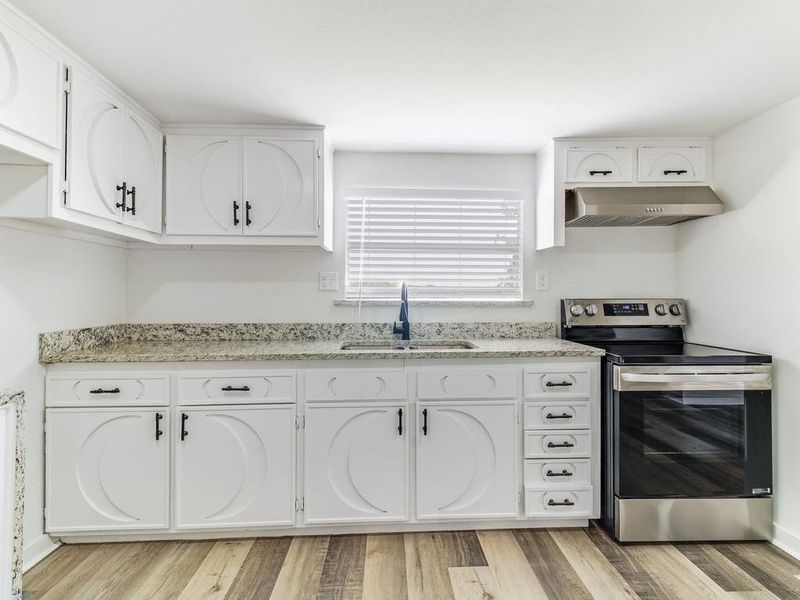 Kitchen with stainless steel range with electric cooktop, range hood, white cabinetry, and light wood-type flooring Kitchen with stainless steel range with electric cooktop, range hood, white cabinetry, and light wood-type flooring