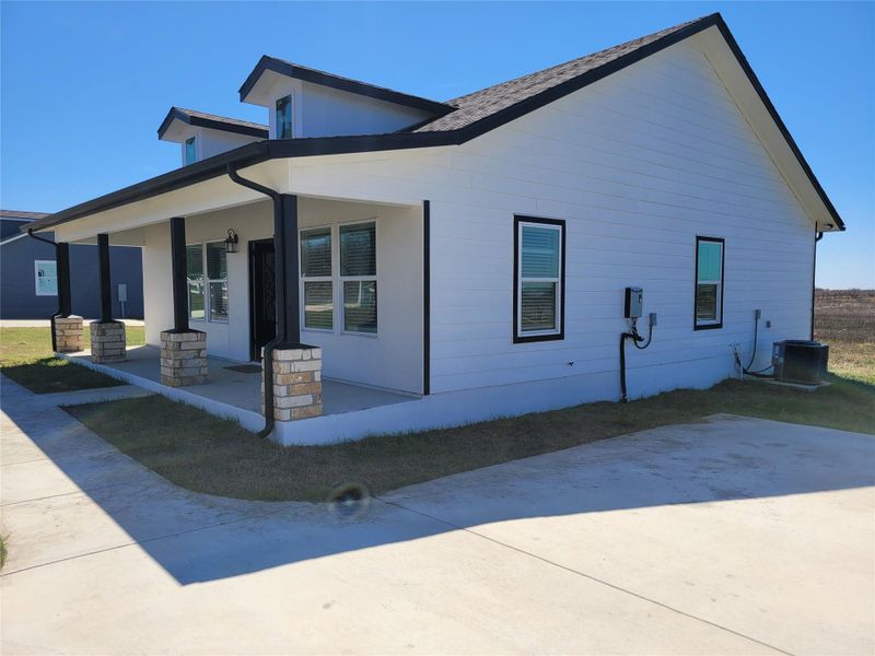 View of side of home featuring covered porch and a cooling unit