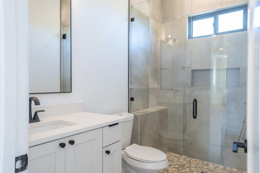 Bathroom featuring vanity, toilet, and a shower with shower door