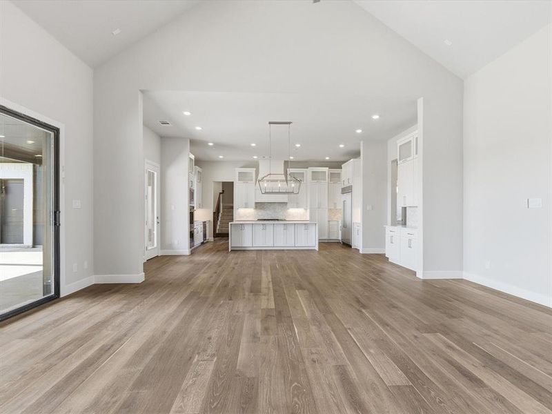 Unfurnished living room with lofted ceiling, recessed lighting, and light wood-style floors Unfurnished living room with lofted ceiling, recessed lighting, and light wood-style floors