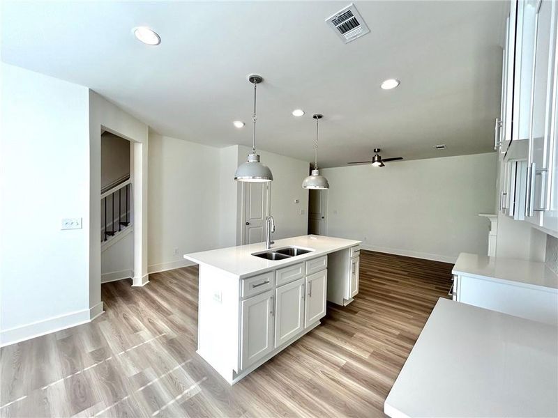 Kitchen featuring sink, light wood-type flooring, ceiling fan, and decorative light fixtures