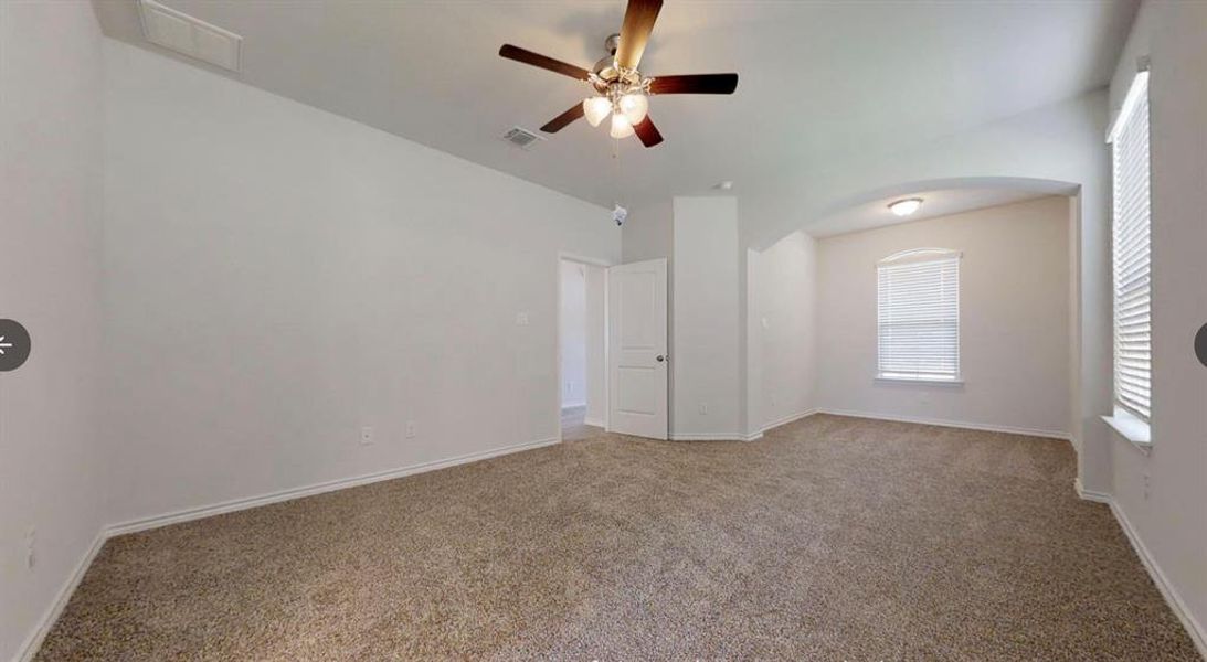 Carpeted spare room with arched walkways, a ceiling fan, and baseboards