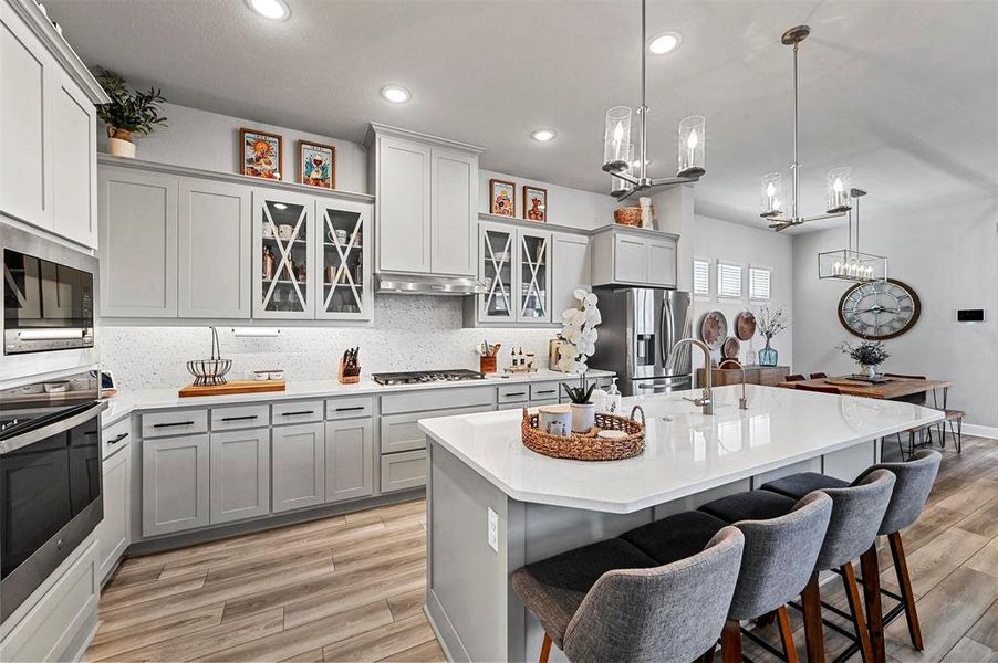 Kitchen featuring stainless steel appliances, a kitchen breakfast bar, light countertops, tasteful backsplash, and recessed lighting Kitchen featuring stainless steel appliances, a kitchen breakfast bar, light countertops, tasteful backsplash, and recessed lighting