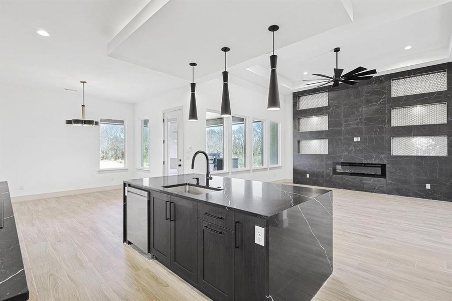 Kitchen featuring dark cabinetry, light wood-style floors, open floor plan, hanging light fixtures, and recessed lighting Kitchen featuring dark cabinetry, light wood-style floors, open floor plan, hanging light fixtures, and recessed lighting