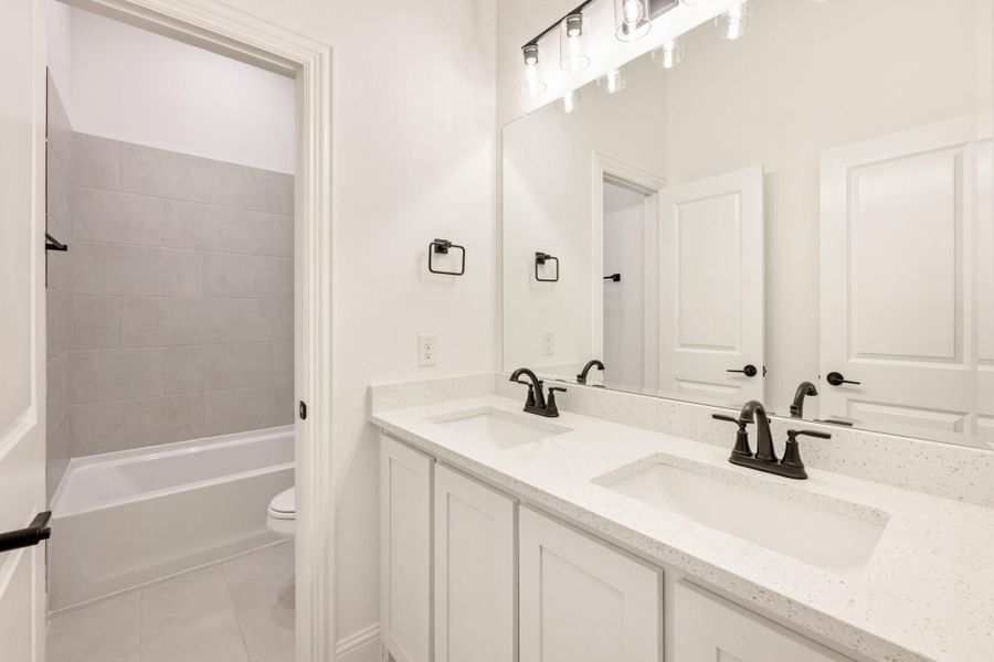 Bathroom with double sink vanity, white quartz countertop, and separate tub-shower room with gray tile