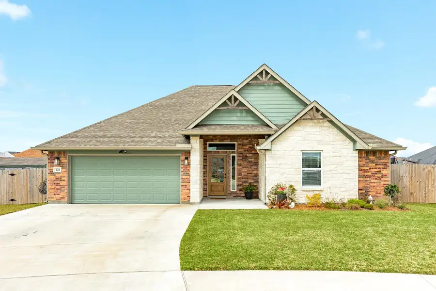 This charming single-story home features a mix of brick and stone exterior with a welcoming front porch. It has a two-car garage, a neatly maintained lawn, and a fenced backyard, perfect for family and guests.