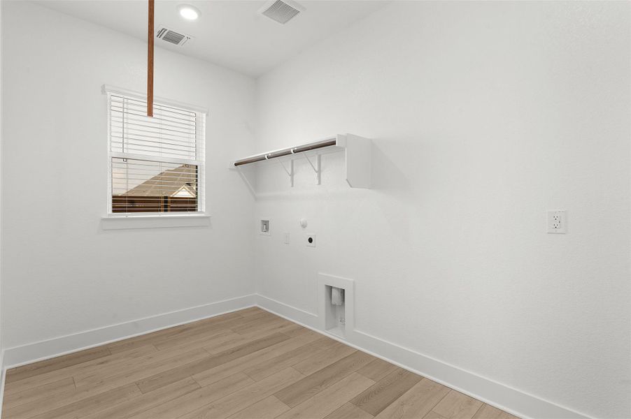 Laundry area with light wood-type flooring, electric dryer hookup, hookup for a washing machine, gas dryer hookup, and recessed lighting