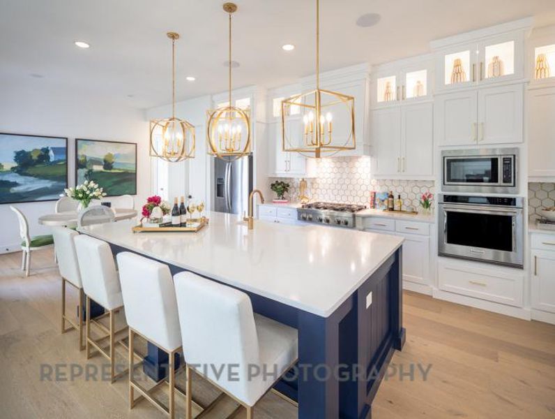 Kitchen featuring stainless steel appliances, an inviting chandelier, light wood-type flooring, and tasteful backsplash Kitchen featuring stainless steel appliances, an inviting chandelier, light wood-type flooring, and tasteful backsplash