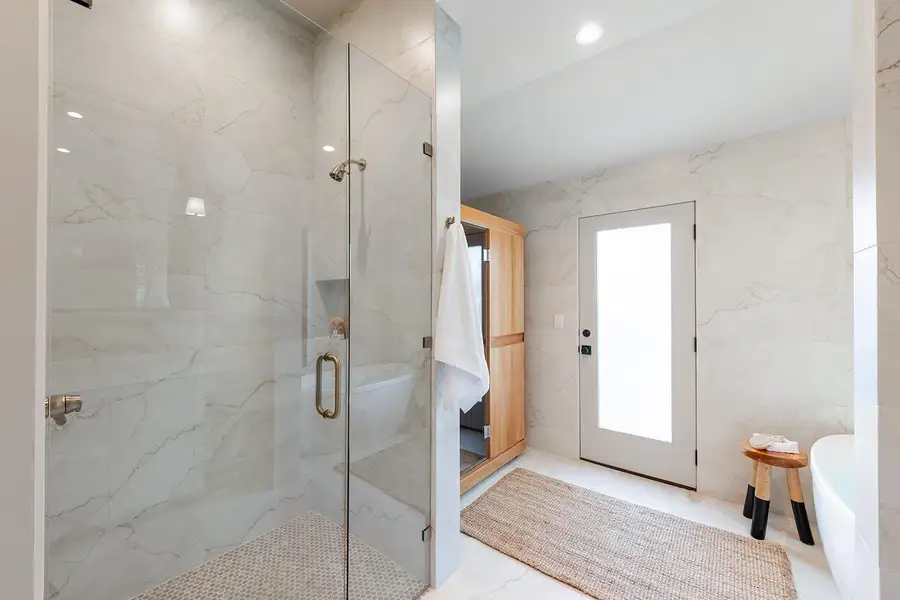 Full bathroom featuring a marble finish shower, tile walls, recessed lighting, and a freestanding tub