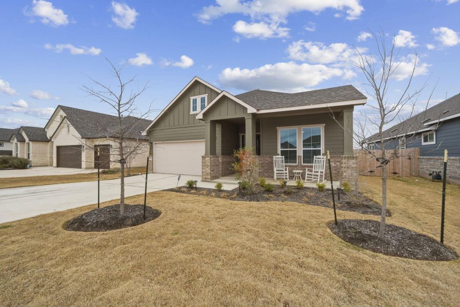 Craftsman-style home with board and batten siding, covered porch, concrete driveway, brick siding, and roof with shingles