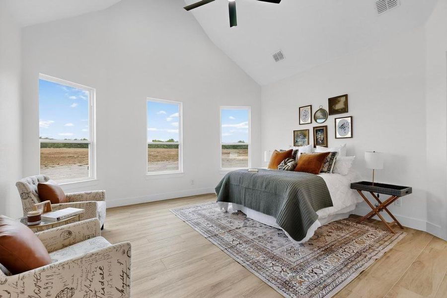 Bedroom with high vaulted ceiling, light wood finished floors, and ceiling fan Bedroom with high vaulted ceiling, light wood finished floors, and ceiling fan