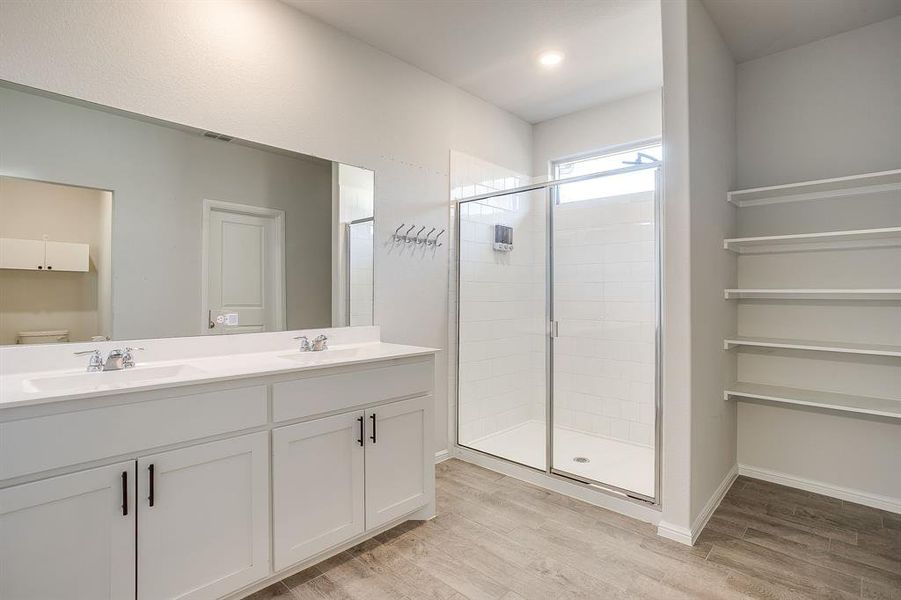 Full bathroom featuring light wood-style flooring, double vanity, and a stall shower