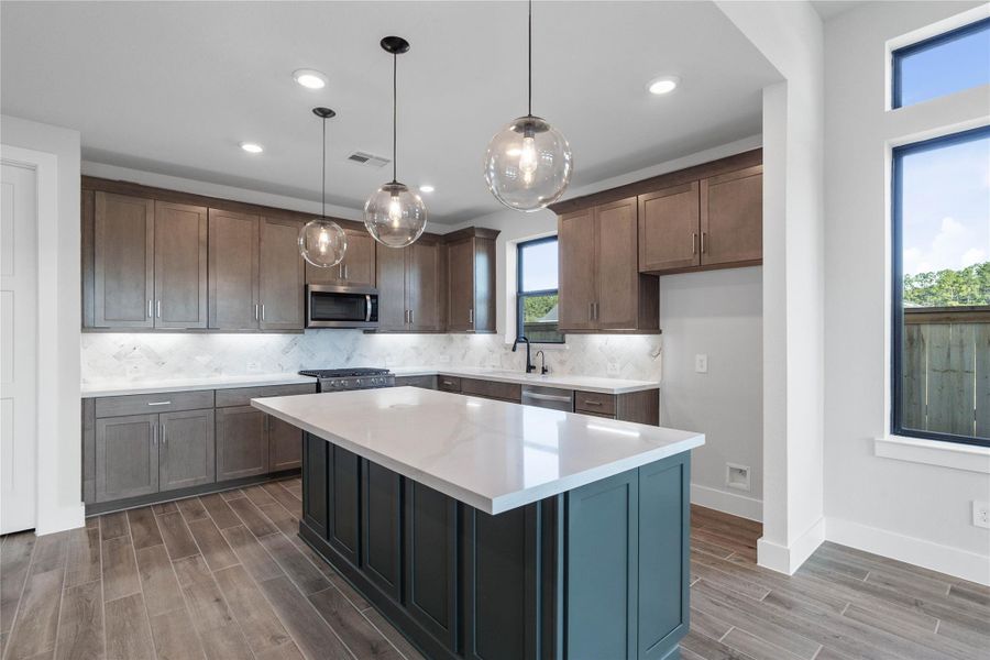 The oversized kitchen island serves as the stunning centerpiece of this modern culinary space, offering both a functional work surface and an ideal gathering spot for family and friends. Its striking sage base provides a bold color contrast to the bright quartz countertop - ample room for meal preparation and generous seating. The oversized kitchen island serves as the stunning centerpiece of this modern culinary space, offering both a functional work surface and an ideal gathering spot for family and friends. Its striking sage base provides a bold color contrast to the bright quartz countertop - ample room for meal preparation and generous seating.