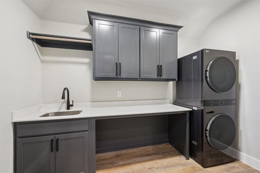 Laundry room featuring stacked washer / drying machine, light wood-style flooring, and cabinet space