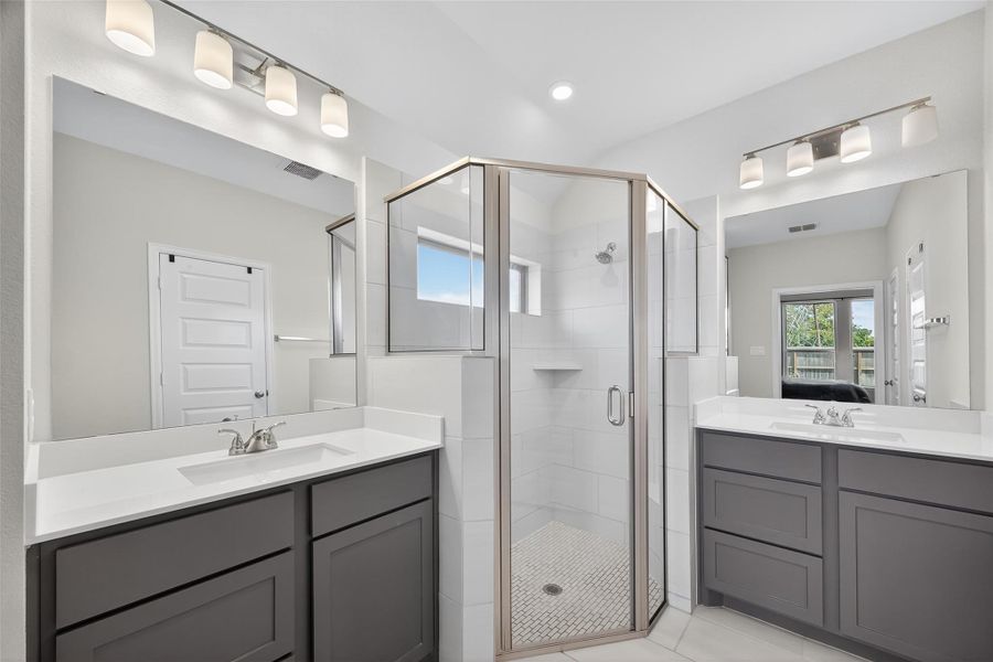 This bathroom features a modern design with dual sinks, sleek dark cabinetry, and a central glass-enclosed shower. Bright lighting and a neutral color palette create a spacious, inviting atmosphere. This bathroom features a modern design with dual sinks, sleek dark cabinetry, and a central glass-enclosed shower. Bright lighting and a neutral color palette create a spacious, inviting atmosphere.