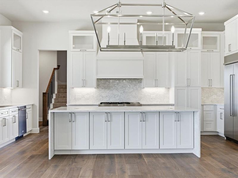 Kitchen featuring glass insert cabinets, light stone countertops, white cabinetry, decorative backsplash, and a kitchen island