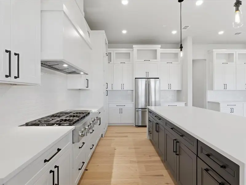 Contemporary kitchen featuring an expansive center island with dark cabinetry and light countertops