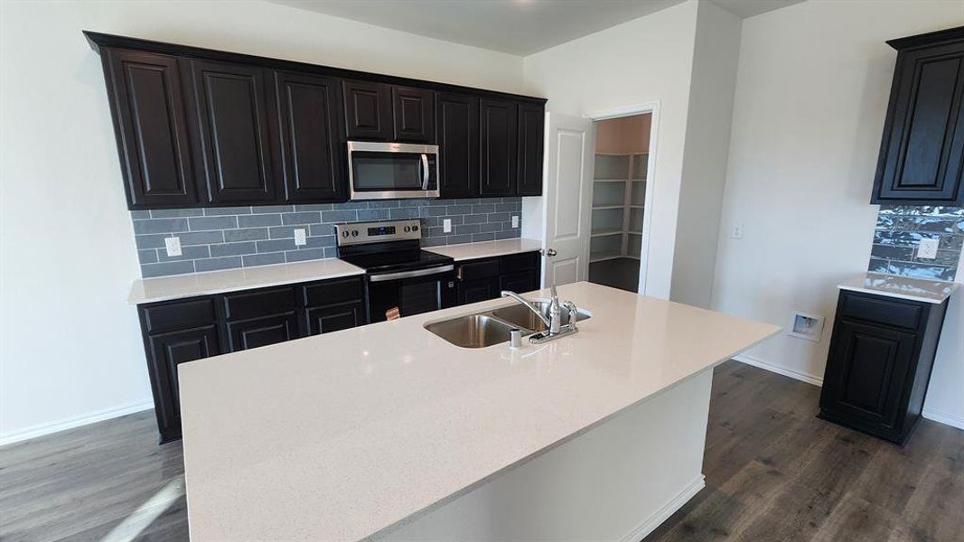 Modern kitchen featuring dark wood-finish cabinetry, white countertops, and a subway tile backsplash Modern kitchen featuring dark wood-finish cabinetry, white countertops, and a subway tile backsplash