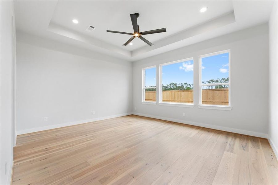 Primary Bedroom with Engineered Hardwood Flooring, Coffered Ceiling, and Fan.