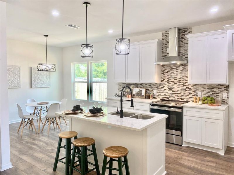 Kitchen featuring stainless steel range, tasteful backsplash, light wood-type flooring, wall chimney exhaust hood, and sink