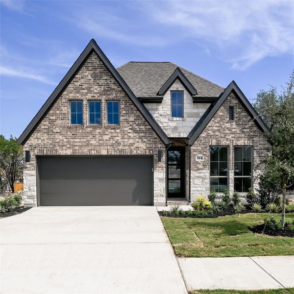 View of front of home with a shingled roof, a garage, concrete driveway, and stone siding