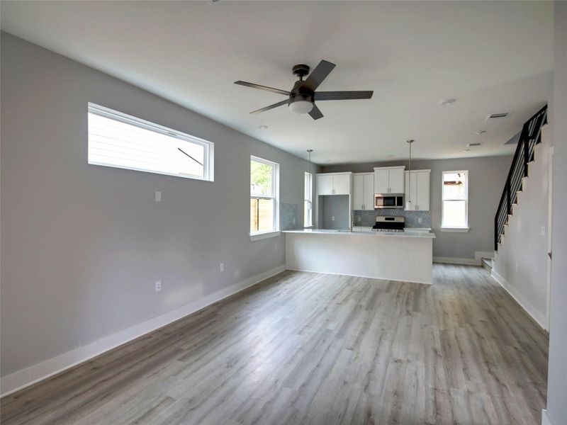 Unfurnished living room featuring light wood-style floors, stairs, and ceiling fan