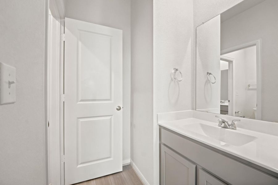 Smooth surfaces and clean lines define this modern bathroom vanity space with light flooring.