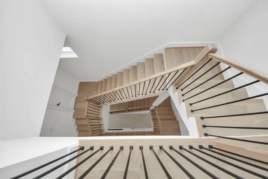 Ascend through this striking architectural moment, where a sculptural staircase becomes a design statement in itself. Warm wood treads contrast beautifully against crisp white walls, while sleek black railings guide your eye upward through the home’s airy vertical space. Bathed in natural light from above, this staircase creates an elegant transition between levels, blending modern design with a sense of openness and flow. Ascend through this striking architectural moment, where a sculptural staircase becomes a design statement in itself. Warm wood treads contrast beautifully against crisp white walls, while sleek black railings guide your eye upward through the home’s airy vertical space. Bathed in natural light from above, this staircase creates an elegant transition between levels, blending modern design with a sense of openness and flow.