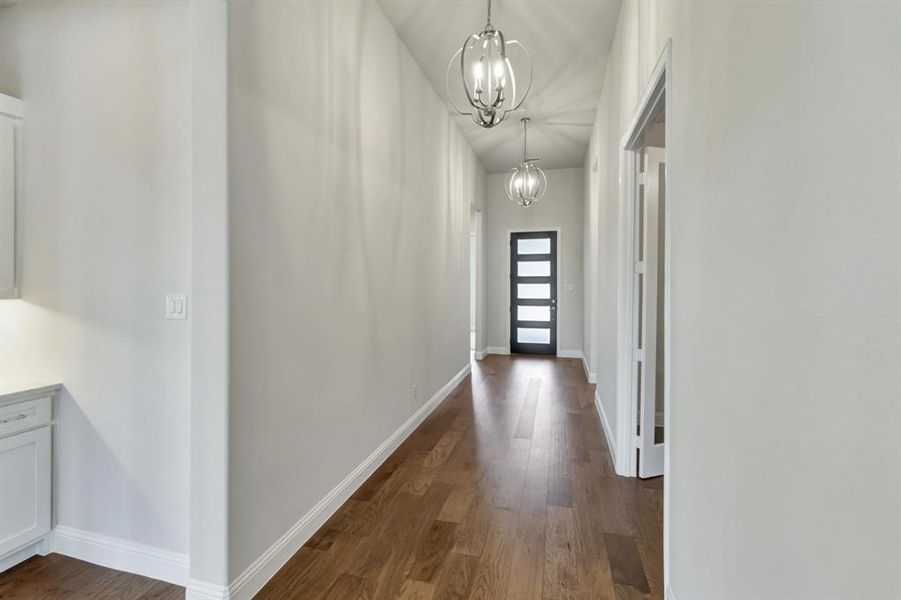 Hallway with dark hardwood / wood-style flooring and an inviting chandelier