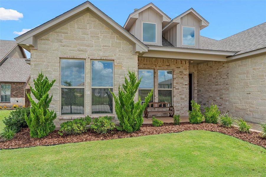 Stone and brick front elevation with landscaped beds and covered entry. Stone and brick front elevation with landscaped beds and covered entry.