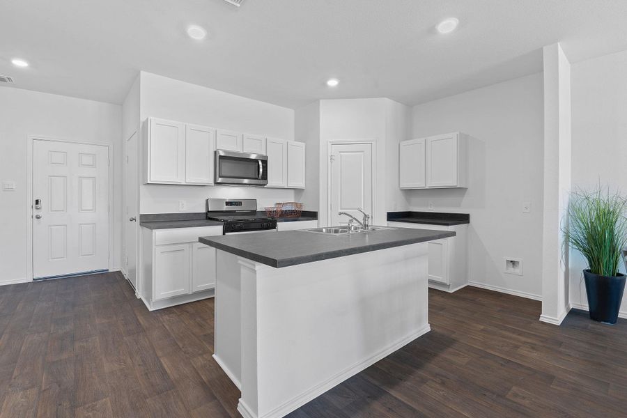 Kitchen featuring stainless steel appliances, dark countertops, a sink, and white cabinets