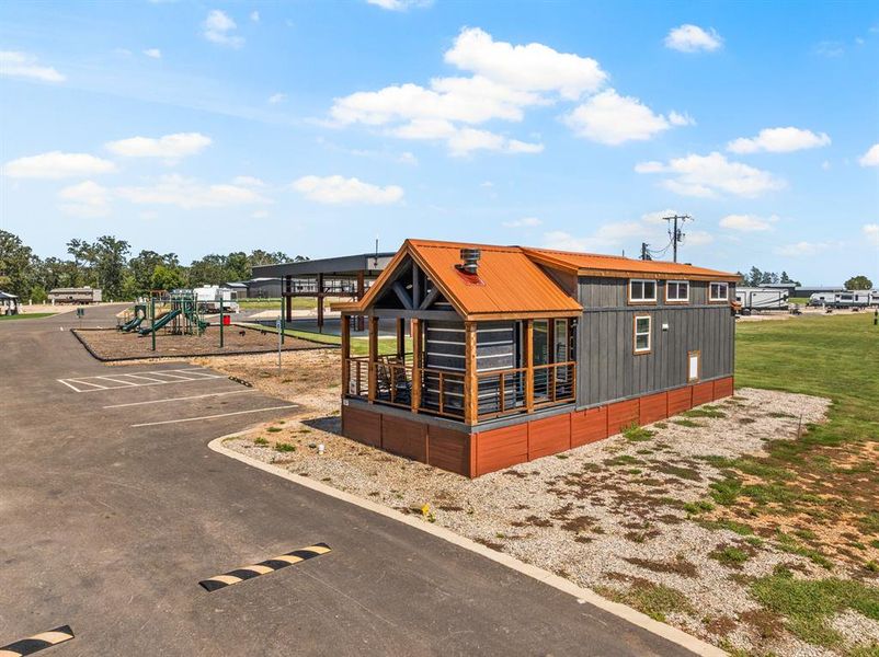 View of side of property featuring a playground, a metal roof, and uncovered parking