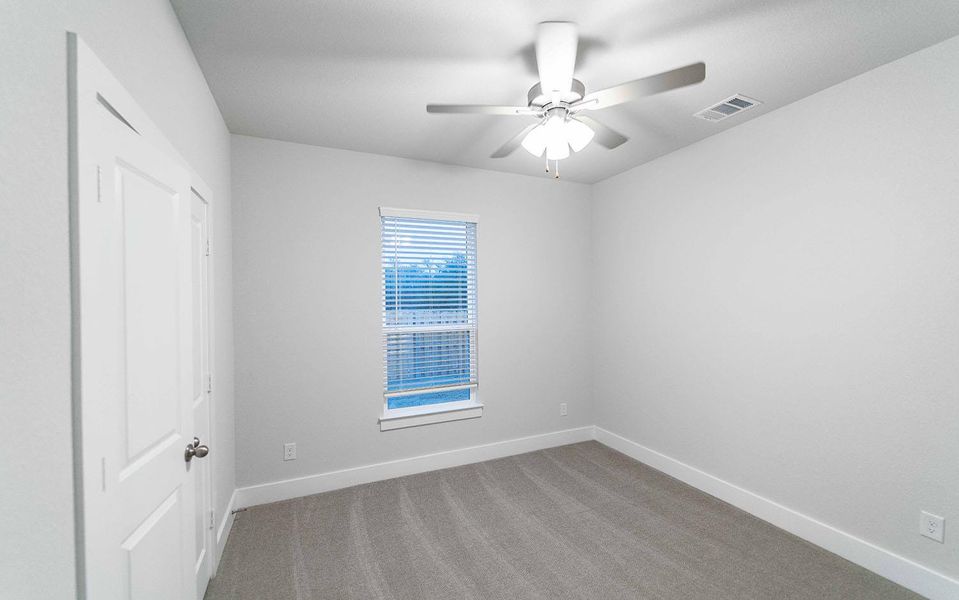 Carpeted empty room featuring a ceiling fan, visible vents, and baseboards