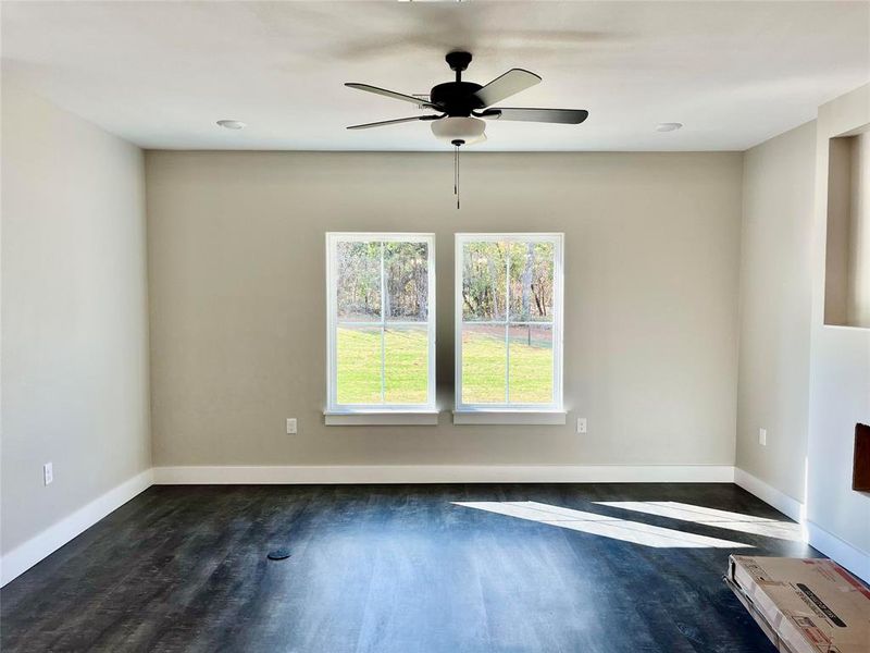 Empty room featuring dark wood-type flooring and ceiling fan