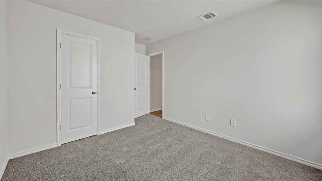 Neutral-toned room featuring grey textured carpeting and white baseboards