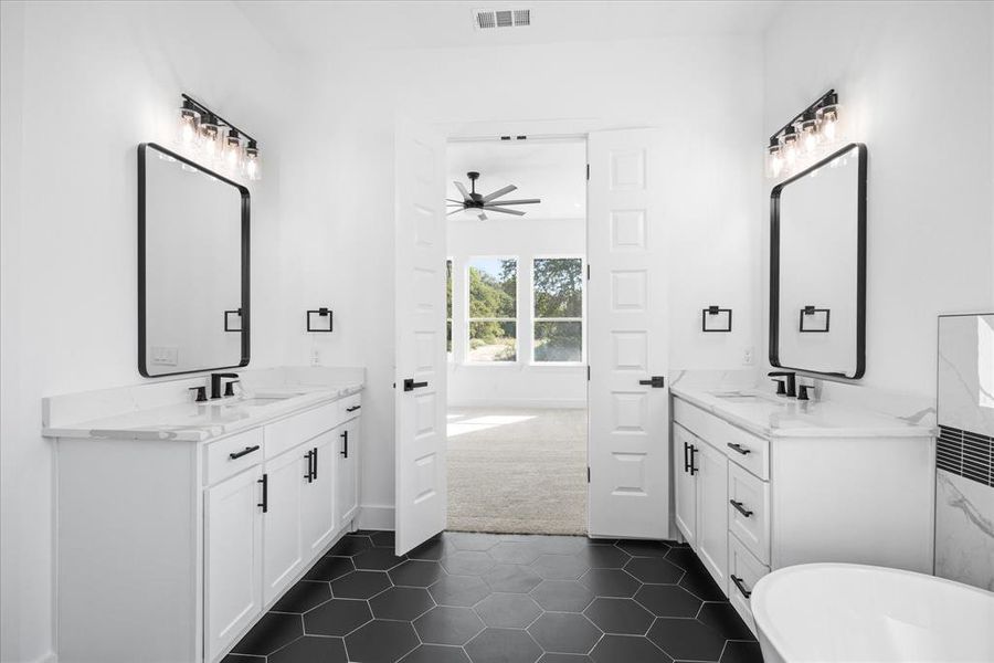 Dual vanities with white cabinetry, black hardware, and stone countertops